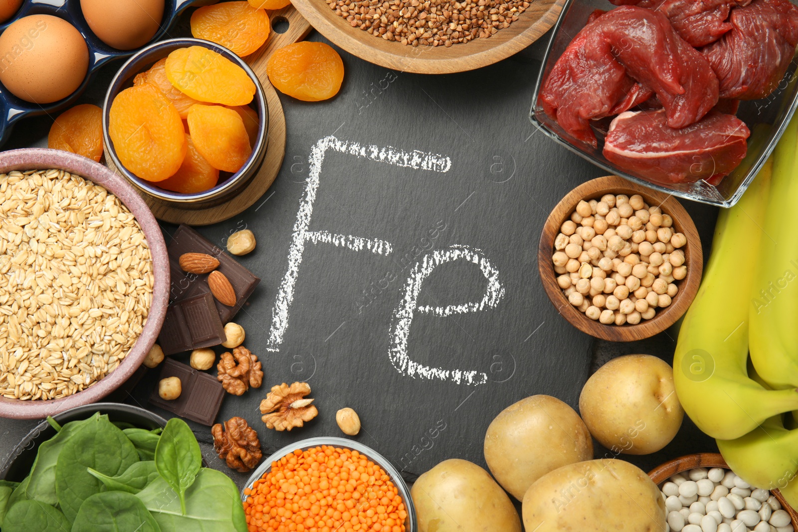 Photo of Diet plan for anemia. Different products rich in iron and slate board with Ferrum symbol on table, flat lay. Space for text