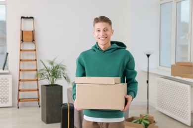 Photo of Happy man with moving boxes in new apartment. Housewarming party