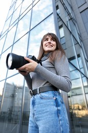 Photo of Professional photographer with digital camera outdoors, low angle view