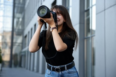 Professional photographer with digital camera near building outdoors