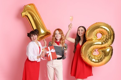 Photo of Coming of age party - 18th birthday. Group of young women celebrating with number shaped balloons on pink background