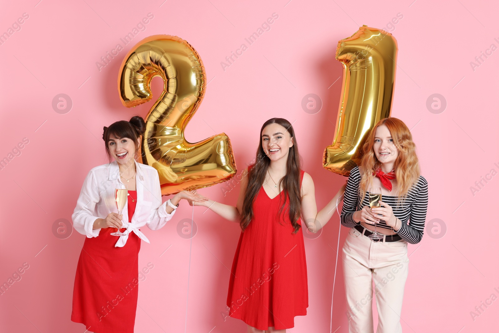 Photo of Coming of age party - 21st birthday. Group of young women celebrating with number shaped balloons on pink background