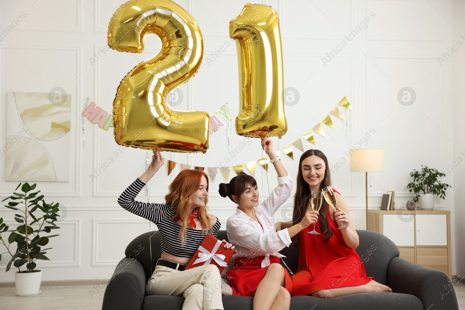 Photo of Coming of age party - 21st birthday. Group of young women celebrating with number shaped balloons at home