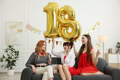 Photo of Coming of age party - 18th birthday. Group of young women celebrating with number shaped balloons at home