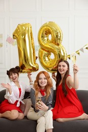 Photo of Coming of age party - 18th birthday. Group of young women celebrating with number shaped balloons at home