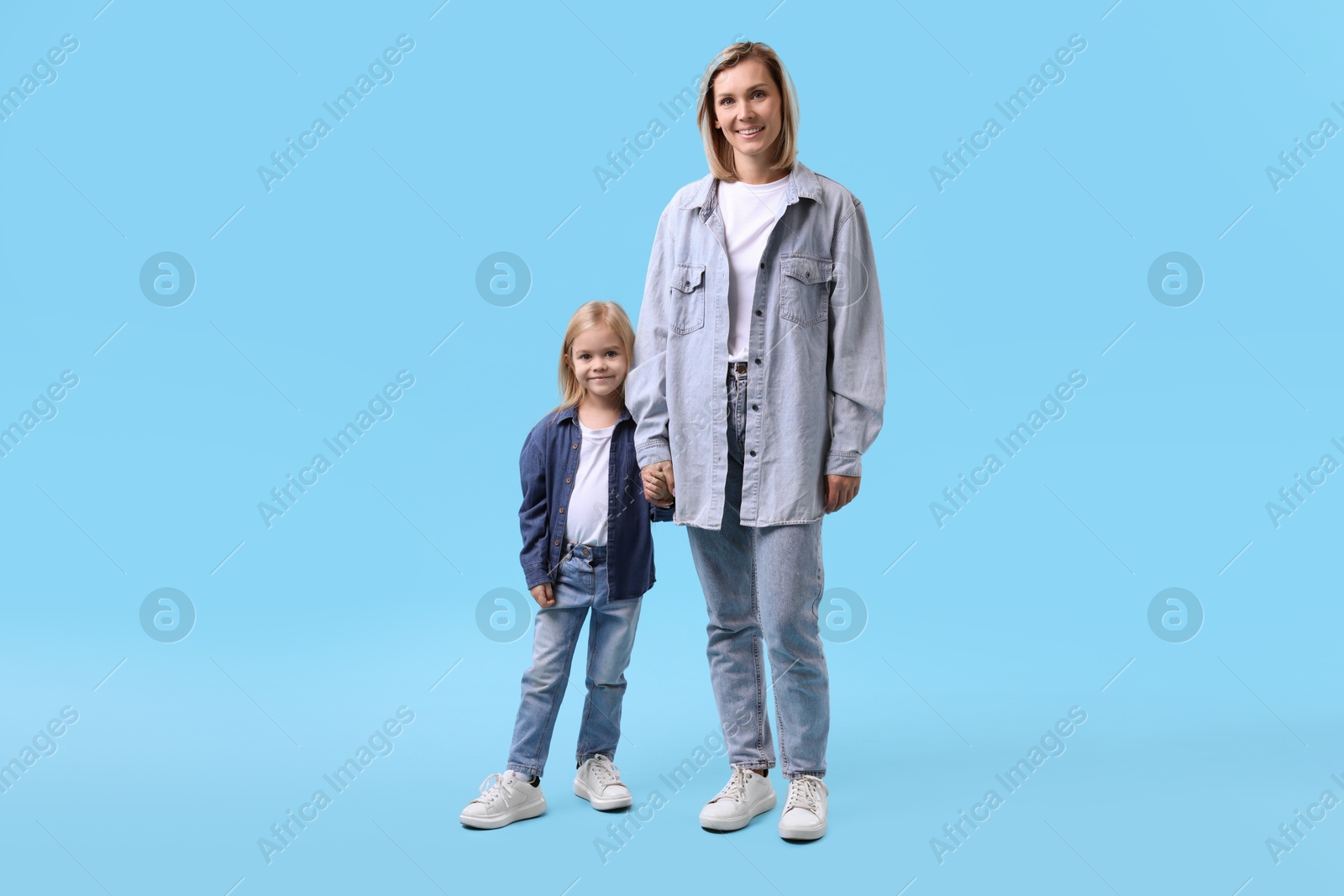 Photo of Cute little girl with her mom on light blue background. Happy Mother's Day