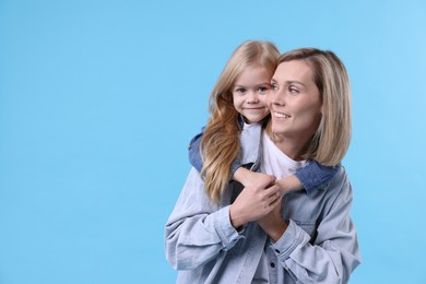 Photo of Cute little girl hugging her mom on light blue background, space for text. Happy Mother's Day