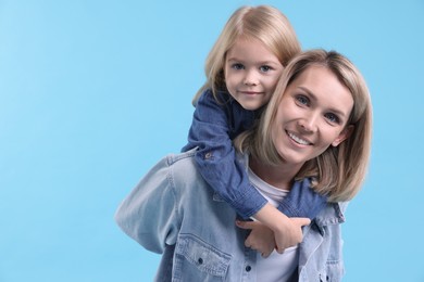 Photo of Cute little girl hugging her mom on light blue background, space for text. Happy Mother's Day