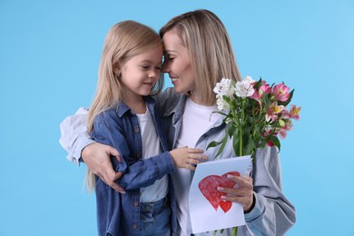 Little daughter congratulating her mom with bouquet of alstroemeria flowers and greeting card on light blue background. Happy Mother's Day