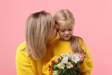 Photo of Woman with her daughter and bouquet of alstroemeria flowers on pink background. Mother's Day celebration