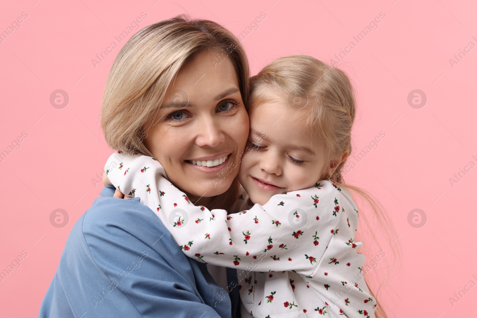 Photo of Cute little girl hugging her mom on pink background. Happy Mother's Day