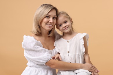 Photo of Cute little girl with her mom on beige background. Happy Mother's Day