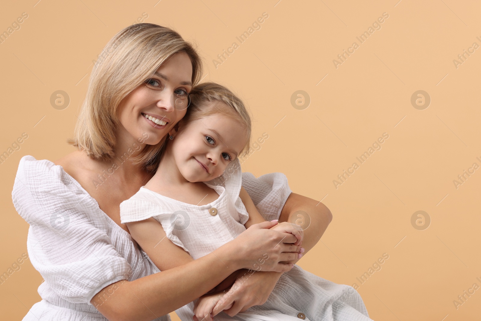 Photo of Cute little girl with her mom on beige background, space for text. Happy Mother's Day