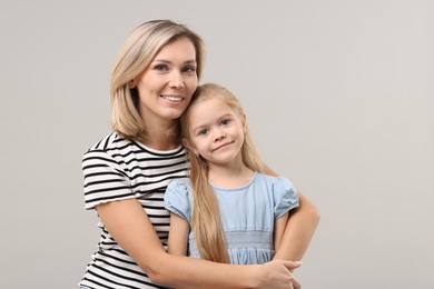 Photo of Cute little girl with her mom on gray background. Happy Mother's Day