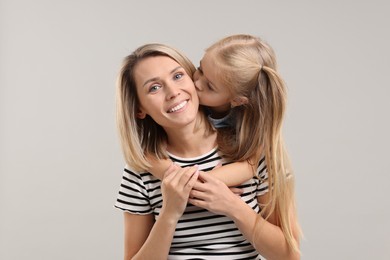 Photo of Cute little girl with her mom on gray background. Happy Mother's Day