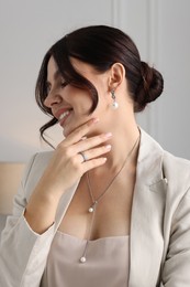 Photo of Beautiful young woman wearing elegant jewelry indoors