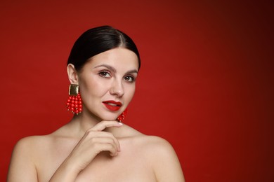 Photo of Beautiful young woman wearing elegant earrings on red background. Space for text