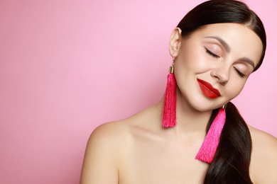 Photo of Beautiful young woman wearing stylish earrings on pink background. Space for text