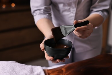 Photo of Spa worker with cosmetic product for chocolate body wrap near woman in salon, closeup. Space for text