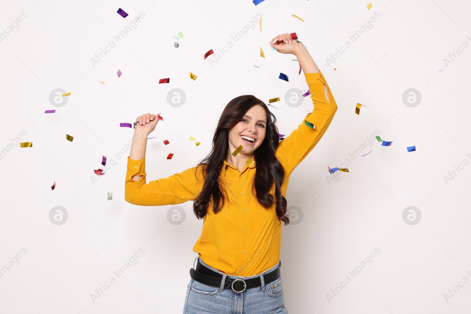 Photo of Happy woman under falling confetti on white background. Surprise party