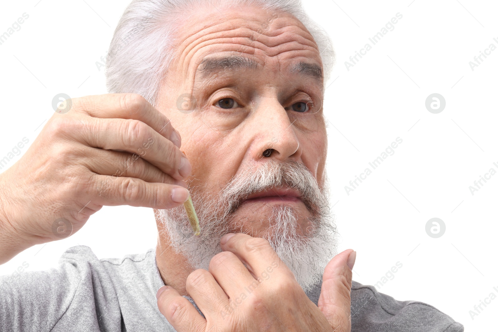 Photo of Senior man applying oil onto his beard on white background