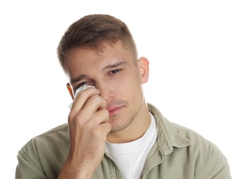 Crying man wiping tears with tissue on white background