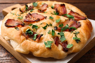 Photo of Delicious focaccia bread with bacon and parsley on wooden table, closeup