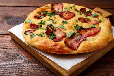 Photo of Delicious focaccia bread with bacon and parsley on wooden table, closeup