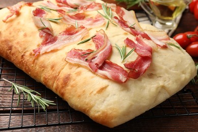 Photo of Delicious focaccia bread with bacon and rosemary on wooden table, closeup