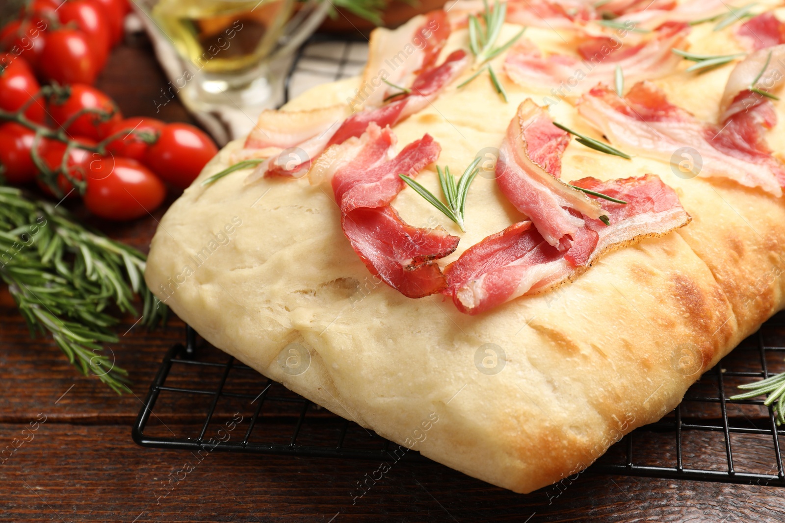 Photo of Delicious focaccia bread with bacon and rosemary on wooden table, closeup