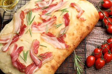 Photo of Delicious focaccia bread with bacon and rosemary on wooden table, closeup