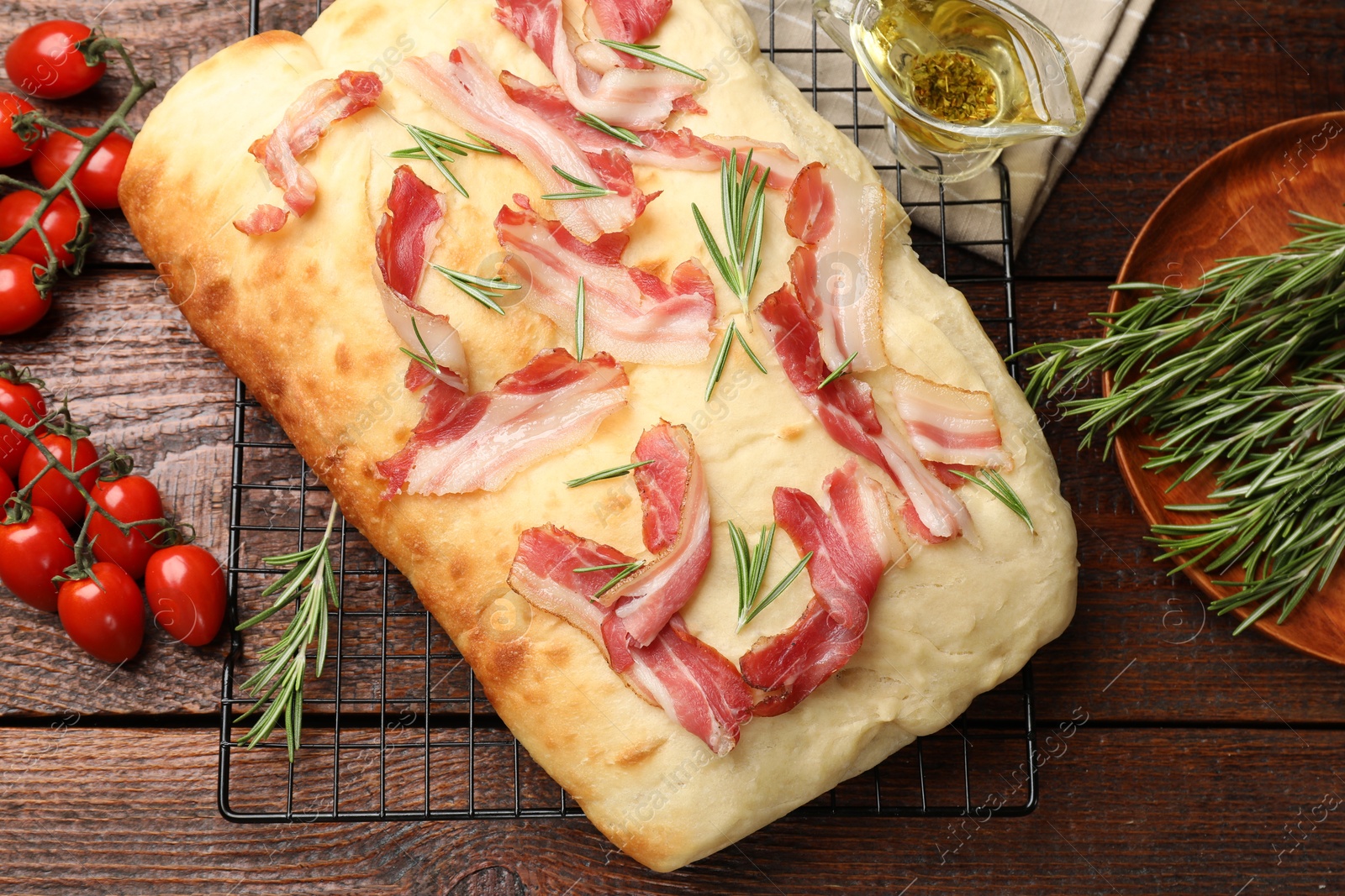 Photo of Delicious focaccia bread with bacon and rosemary on wooden table, flat lay