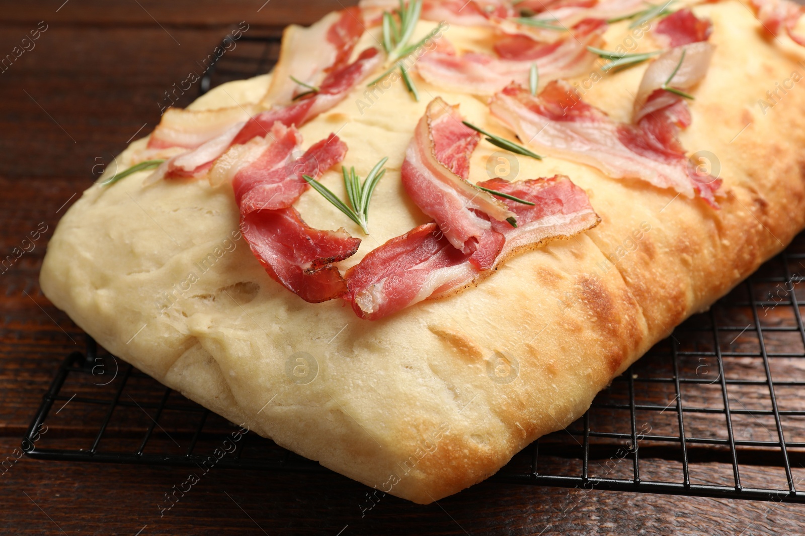 Photo of Delicious focaccia bread with bacon and rosemary on wooden table, closeup