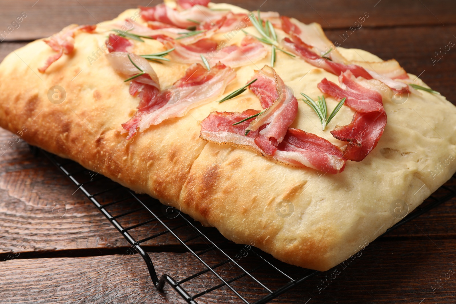 Photo of Delicious focaccia bread with bacon and rosemary on wooden table, closeup