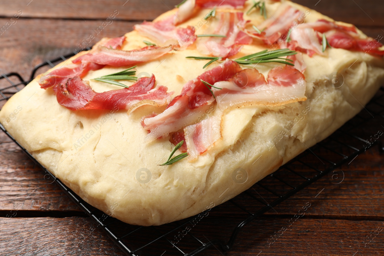 Photo of Delicious focaccia bread with bacon and rosemary on wooden table, closeup