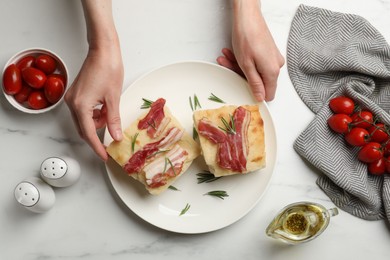 Photo of Woman serving delicious focaccia bread at white table, top view