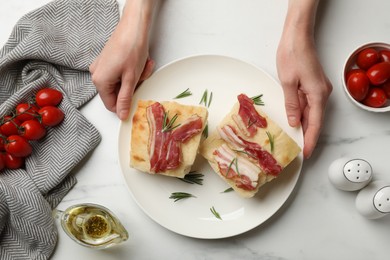 Photo of Woman serving delicious focaccia bread at white table, top view