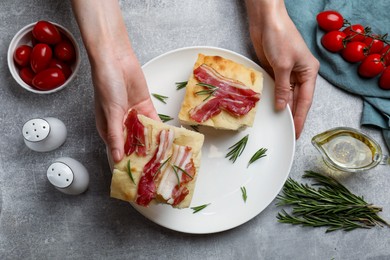 Photo of Woman serving delicious focaccia bread at grey table, top view