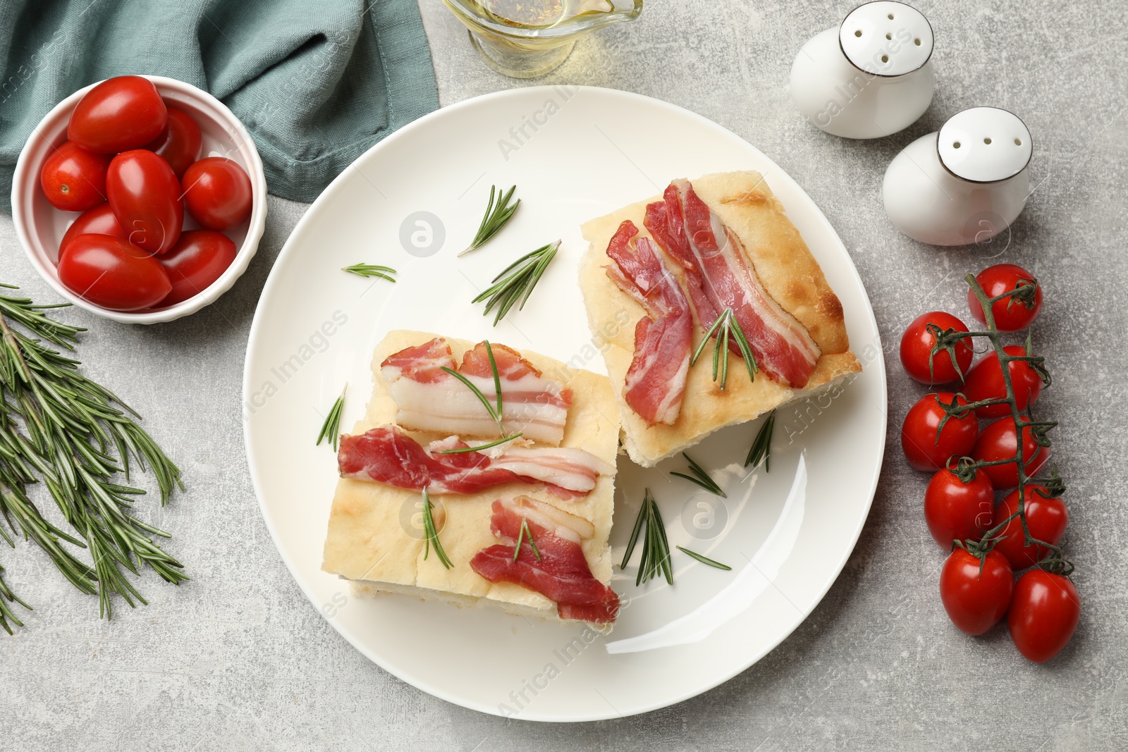 Photo of Pieces of delicious focaccia bread with bacon served on grey table, flat lay