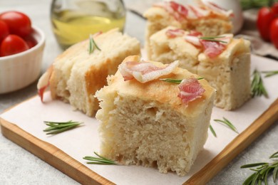 Photo of Pieces of delicious focaccia bread with bacon served on grey table, closeup