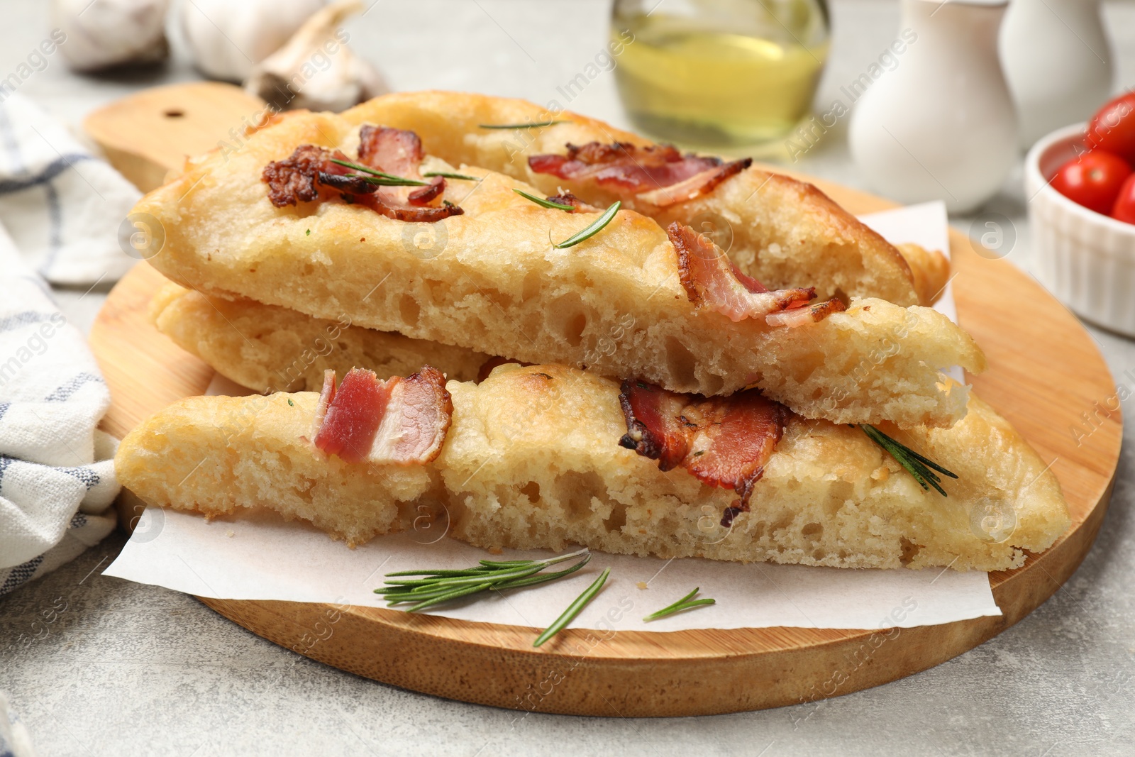 Photo of Pieces of delicious focaccia bread with bacon served on grey table, closeup