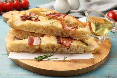 Photo of Pieces of delicious focaccia bread with bacon served on blue wooden table, closeup