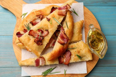 Photo of Pieces of delicious focaccia bread with bacon served on blue wooden table, top view