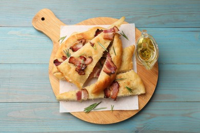 Photo of Pieces of delicious focaccia bread with bacon served on blue wooden table, top view