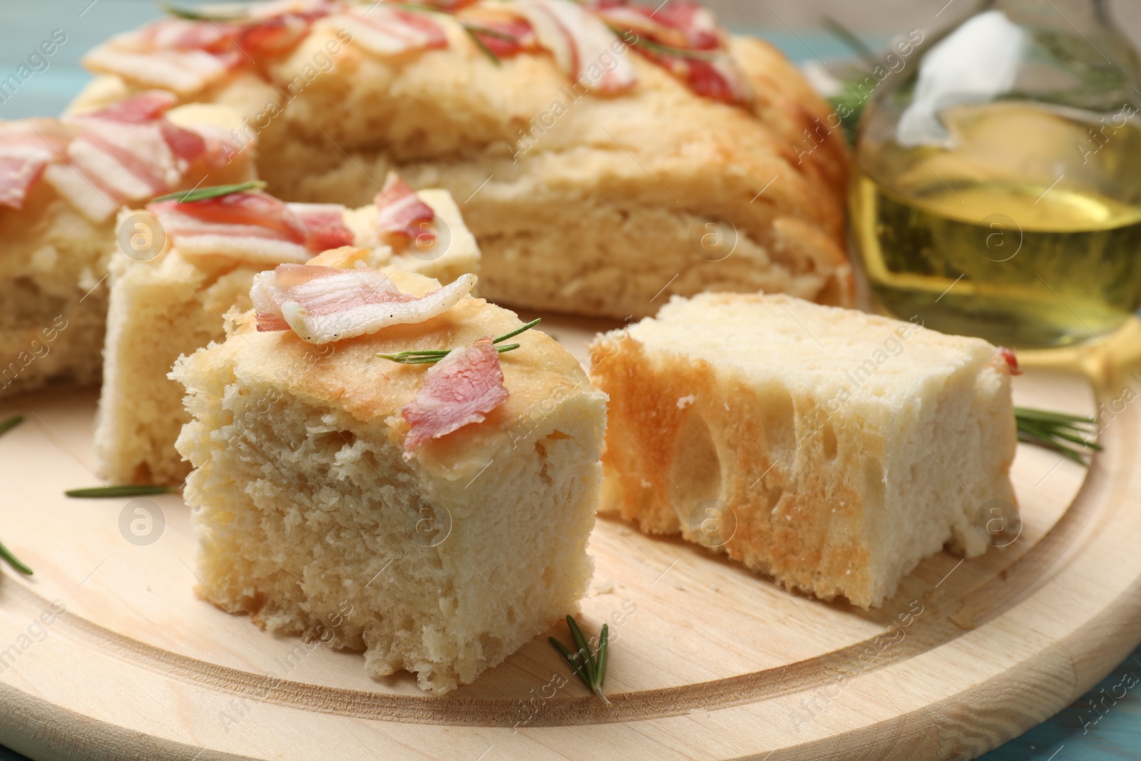 Photo of Pieces of delicious focaccia bread with bacon served on blue wooden table, closeup