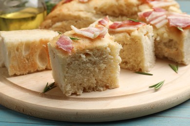 Photo of Pieces of delicious focaccia bread with bacon served on blue wooden table, closeup