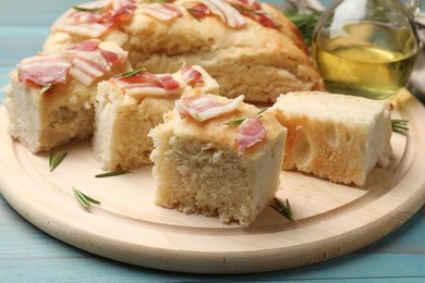 Photo of Pieces of delicious focaccia bread with bacon served on blue wooden table, closeup