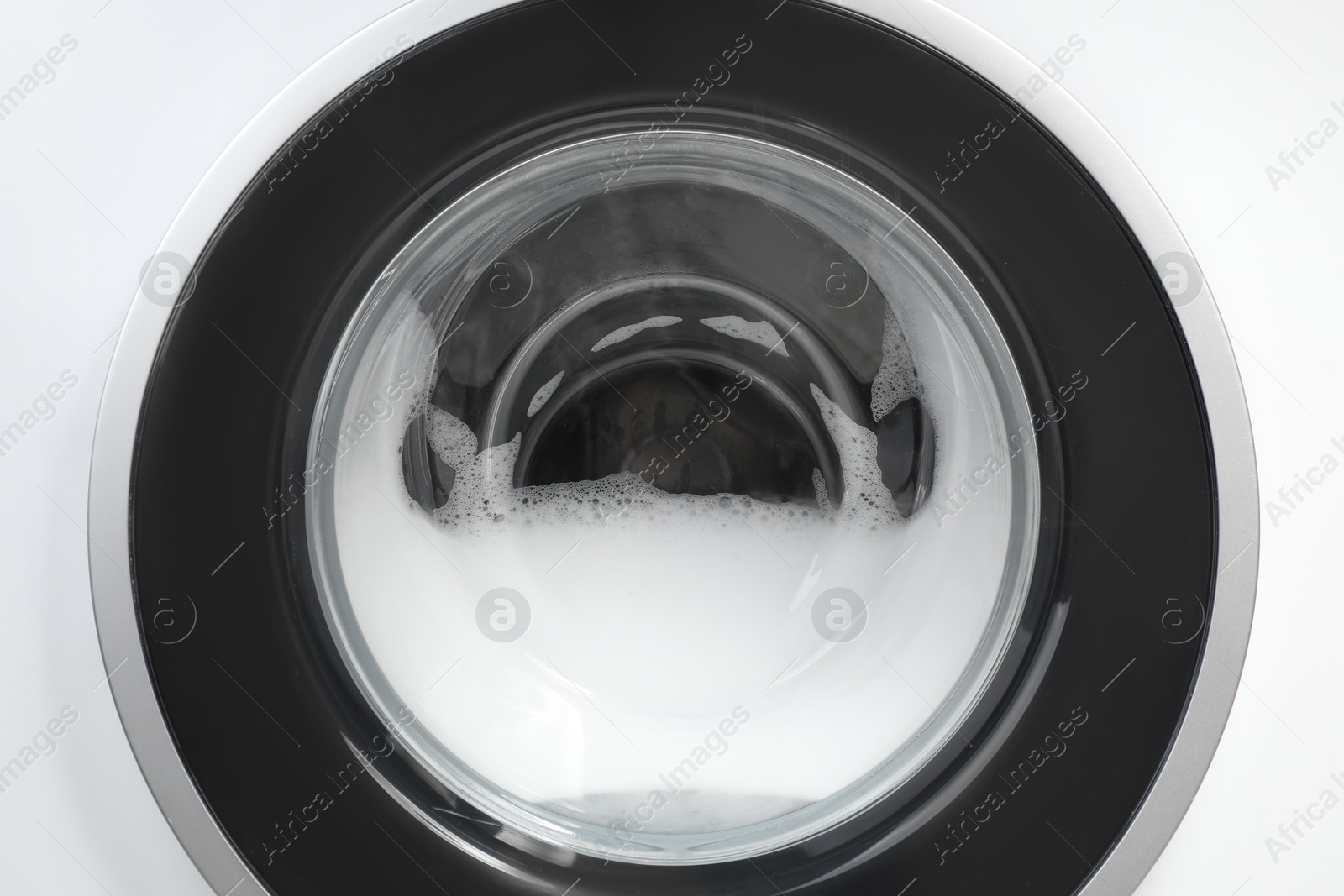 Photo of Washing machine with suds as background, closeup