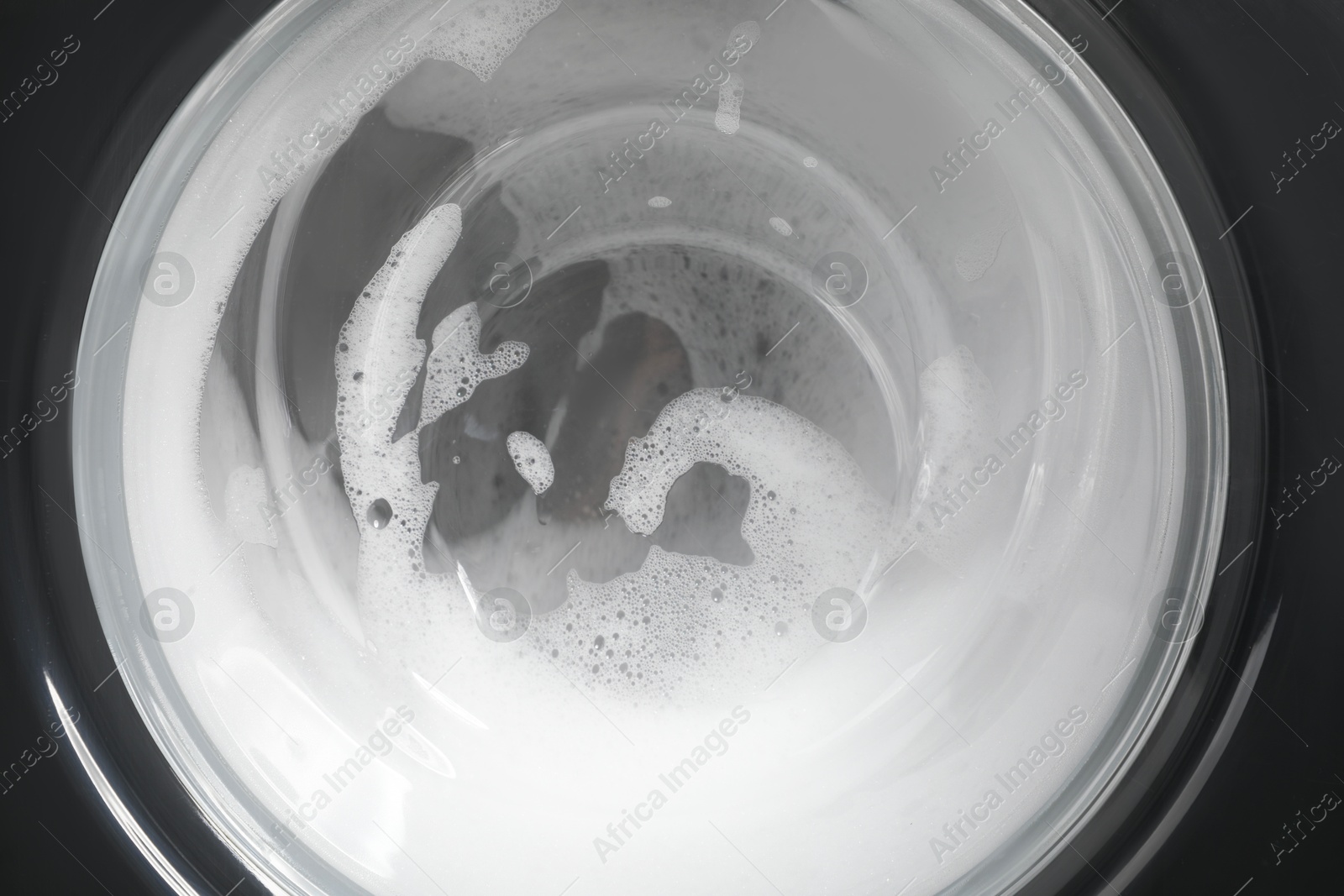 Photo of Washing machine with suds as background, closeup