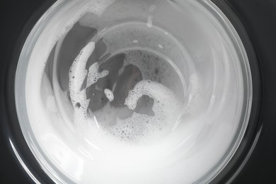 Photo of Washing machine with suds as background, closeup